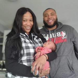 Family of 3: Mother, father and baby. Mother holding the baby.