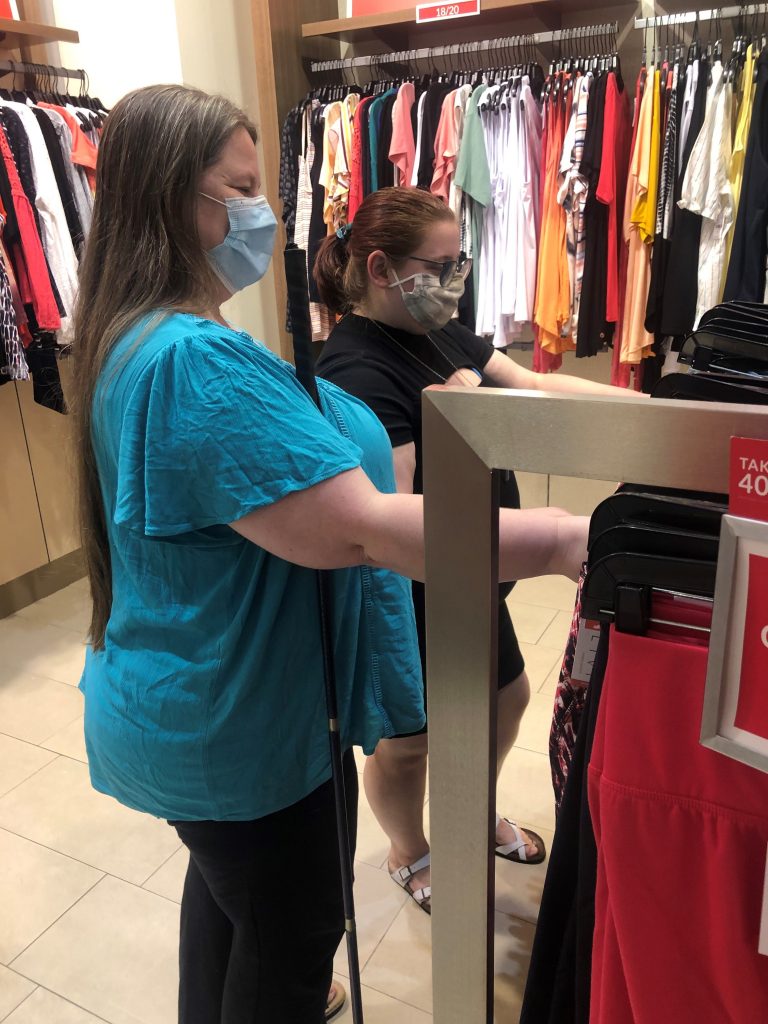 Two people wearing masks looking at clothes.