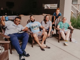 Image of 3 people sitting and one standing bent over. 