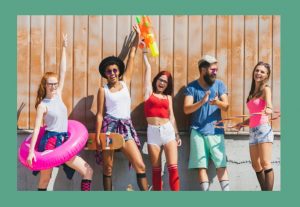 Image of a group of five diverse individuals with bright colored clothing standing in front of a light brown and gray stained wall. Several of the individuals are hold a summer sports one of four summer sports items: pool tube, skate board, water gun and hulahoop. 
