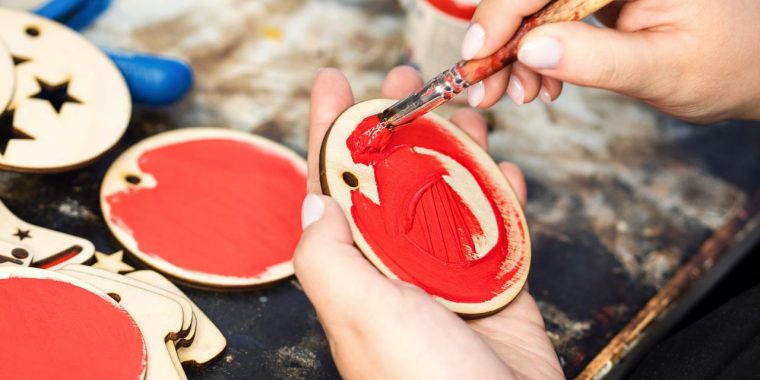 Image of a hand painting wooden ornaments.