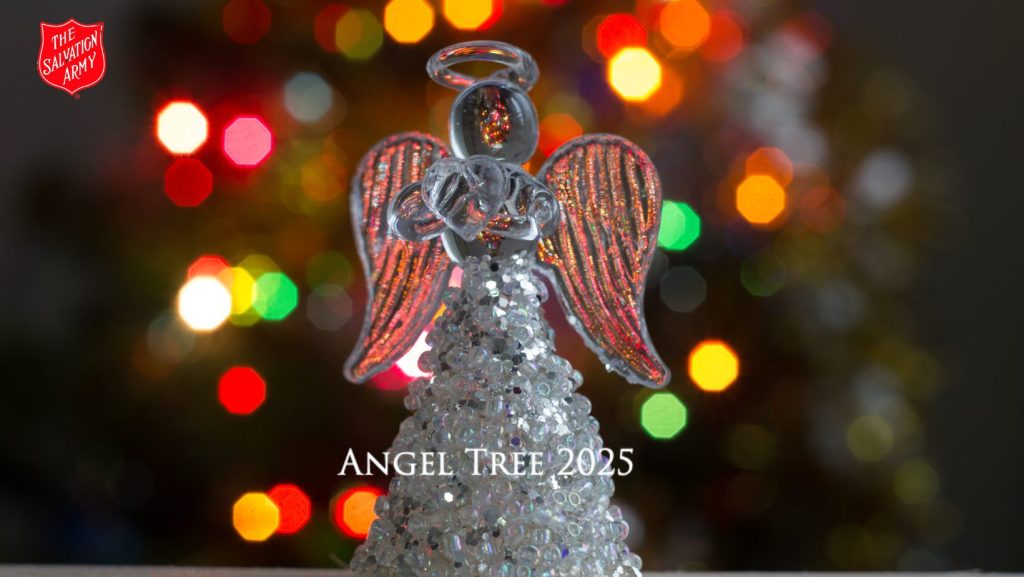 A decorative glass angel figurine with shimmering beads and glittery wings is placed in front of a colorful, blurred background of holiday lights. The Salvation Army logo appears in the top left corner, and the text “Angel Tree 2025” is displayed near the bottom.