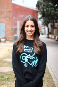 Headshot of Lauren Morris, founder and executive director of MOVE Inclusive Dance, smiles for the camera, wearing a black t-shirt with teal accents.